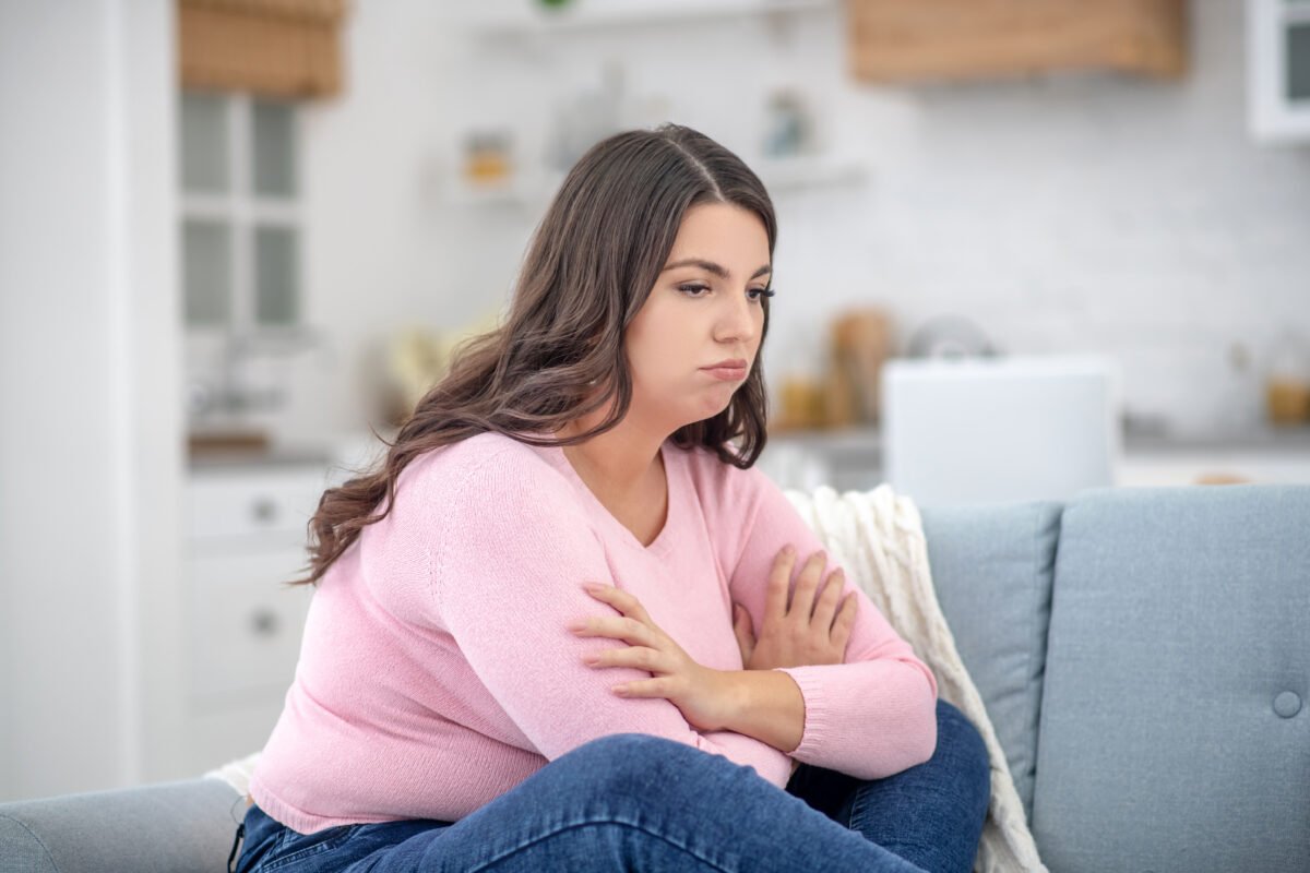 Bad mood. Full-figured young woman in a pink shirt feeling depressed